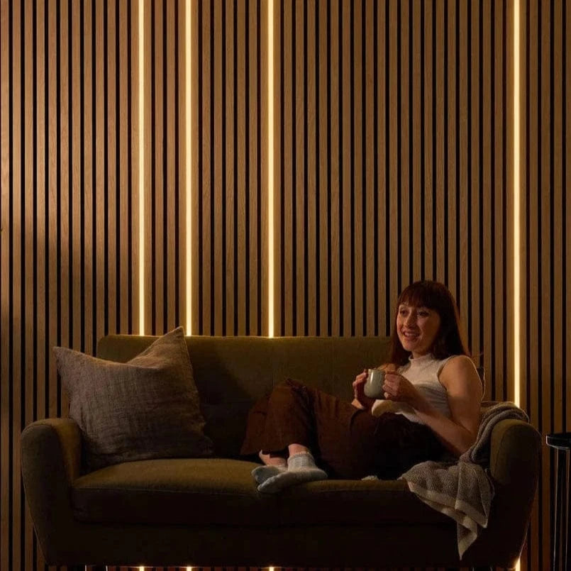 Woman sitting on a couch in a dimly lit room with vertical light strips on the wall.